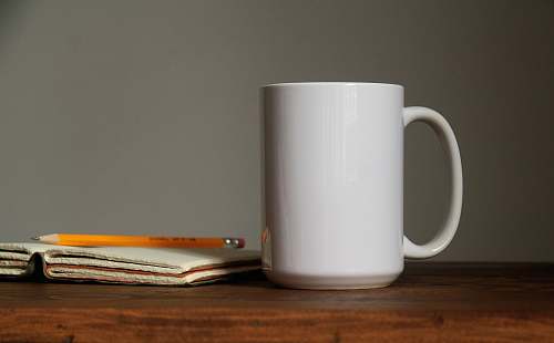 coffee cup white ceramic mug beside orange pencil on open book page atlanta